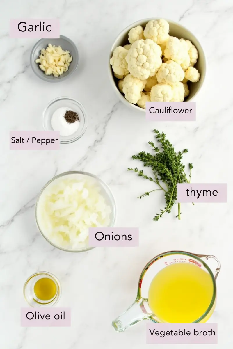 Roasted cauliflower soup served in a white bowl, topped with fresh herbs and a drizzle of olive oil
