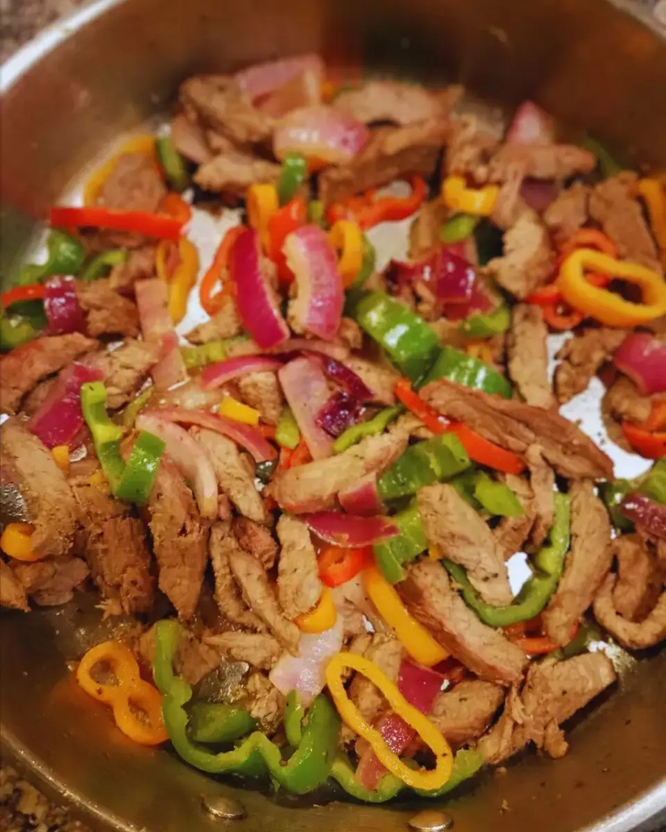 Juicy steak fajitas served with colorful bell peppers and onions on a sizzling hot skillet.