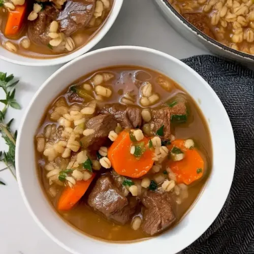 A bowl of hearty beef barley soup with vegetables and tender beef in rich broth.